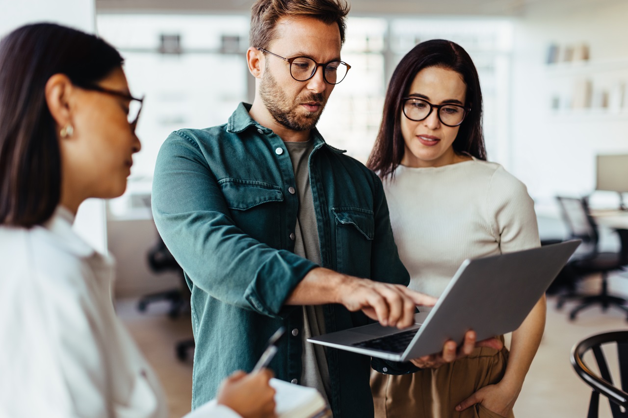 Group of business people using a laptop and having a discussion in an office